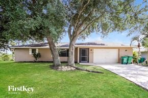 Port Charlotte house for rent - a home with a tree in the yard and a garage door