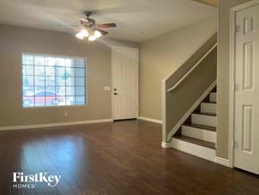 Phoenix house for rent - A spacious room with wooden floors and a staircase leading to another level.