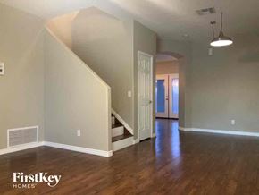 Phoenix house for rent - A spacious room with wooden floors and a staircase leading to another room.