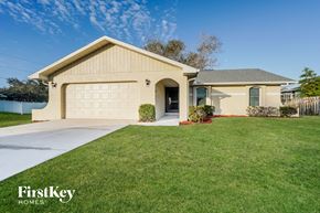 Fort Myers house for rent - a beige house with a garage door and a lawn