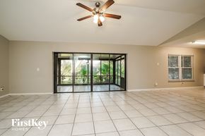 Fort Myers house for rent - an empty living room with a ceiling fan and a sliding glass door