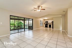 Fort Myers house for rent - an empty living room with a ceiling fan and sliding glass doors