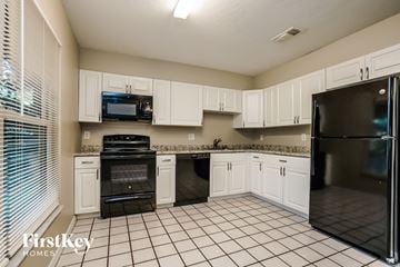Fort Myers house for rent - a kitchen with white cabinets and black appliances