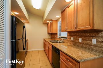 Fort Myers house for rent - a kitchen with wood cabinets and granite counter tops and a black refrigerator
