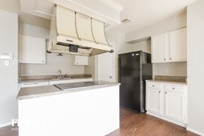 Houston house for rent - an empty kitchen with white cabinets and a black refrigerator