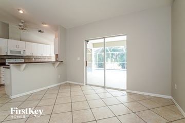 Fort Myers house for rent - A kitchen with a tile floor and a sliding glass door leading to a backyard.