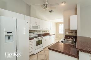Fort Myers house for rent - A kitchen with white appliances and a brown countertop.