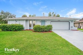 Fort Myers house for rent - A white house with a garage door and a driveway in front.