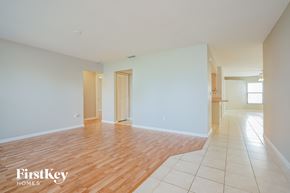 Fort Myers house for rent - A room with wooden floors and white walls, with a door on the left and a window on the right.