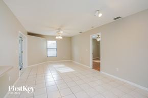 Fort Myers house for rent - A spacious empty room with a fan and a doorway leading to another room.