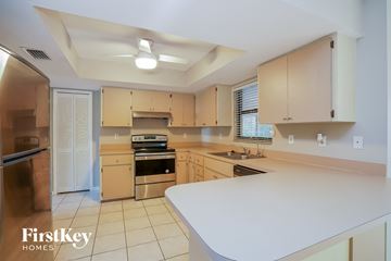 Fort Myers house for rent - A kitchen with a white counter top and wooden cabinets.