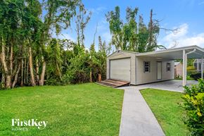 Fort Myers house for rent - A house with a well-maintained lawn and trees in the background.