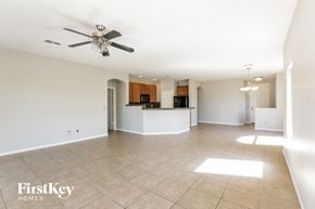 Phoenix house for rent - A spacious room with a ceiling fan and a kitchen area in the background.