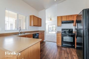 Surprise house for rent - A kitchen with wooden cabinets and a black fridge.