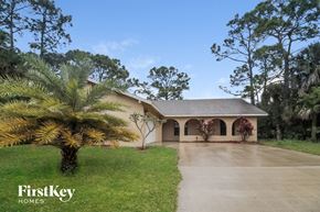 Palm Bay house for rent - A house with a driveway and a palm tree in front of it.