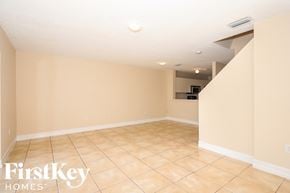 Miami house for rent - A spacious room with beige walls and tiled flooring, with a FirstKey Homes logo in the corner.