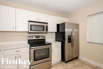 Miami house for rent - A kitchen with a stainless steel refrigerator and a black stove top oven.