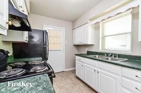 Memphis house for rent - a kitchen with white cabinets and green counter tops and a black stove and refrigerator