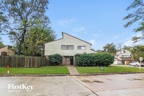 Spring house for rent - A house with a grey facade is situated on a street with a FirstKey Homes sign.