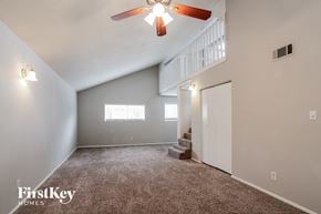 Spring house for rent - A spacious room with a carpeted floor, a ceiling fan, and a staircase leading to another room.