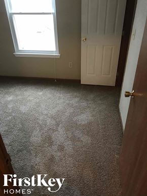 Noblesville house for rent - A carpeted room with a door and a window.