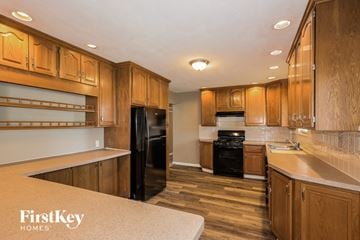 Florissant house for rent - a kitchen with wooden cabinets and black appliances