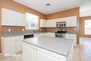 Miramar house for rent - a large kitchen with white cabinets and granite counter tops