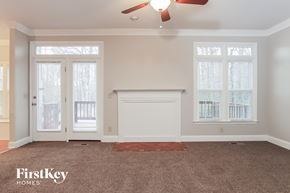 Kernersville house for rent - A room with a carpet, a fireplace, and a ceiling fan.