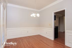 Kernersville house for rent - A room with wooden floors and white walls, with a chandelier hanging from the ceiling.