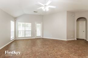 Humble house for rent - A spacious room with a fan and a door leading to another room.