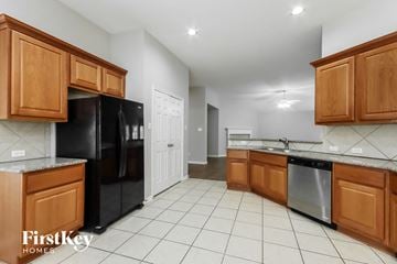 Humble house for rent - A kitchen with wooden cabinets and a black refrigerator.
