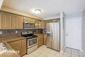 Miami house for rent - a kitchen with stainless steel appliances and wooden cabinets