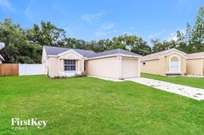Brandon house for rent - a beige house with a grassy yard and a white fence