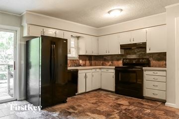 Blue Springs house for rent - A kitchen with a black refrigerator and white cabinets.