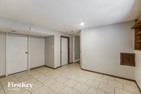 Blue Springs house for rent - A spacious room with a tile floor and white walls, with a wooden shelf on the right wall.
