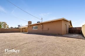 Mesa house for rent - A house with a brown exterior is surrounded by a gravel driveway.