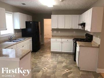 Lawrenceville house for rent - A kitchen with black appliances and white cabinets.