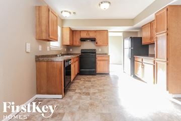Greenwood house for rent - A kitchen with wooden cabinets and a black refrigerator.