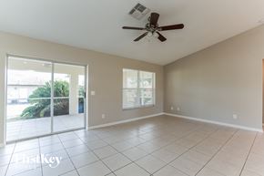 Fort Myers house for rent - an empty living room with a ceiling fan and a sliding glass door