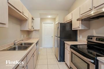 Fort Myers house for rent - a kitchen with white cabinets and black appliances and a black refrigerator