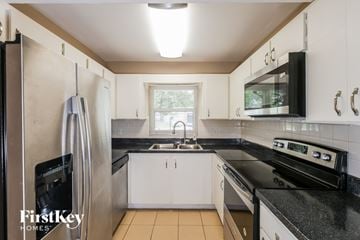 Oldsmar house for rent - A kitchen with a black stove top oven and a black microwave above it.
