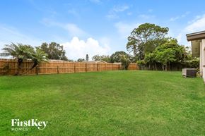 Oldsmar house for rent - A backyard with a fence and trees.
