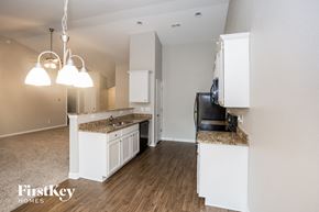 Gastonia house for rent - a kitchen with white cabinets and a counter top and a refrigerator