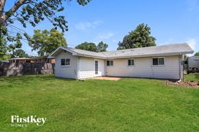 Florissant house for rent - A small house with a garage is surrounded by a grassy yard.