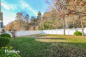Winston-Salem house for rent - a backyard with a white fence and green grass and trees
