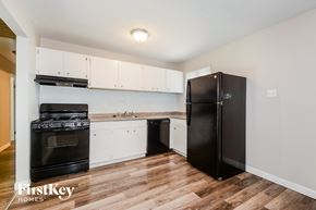 Florissant house for rent - a kitchen with white cabinets and black appliances and a refrigerator