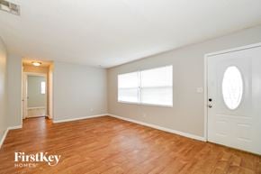 Orlando house for rent - A room with wooden floors and white walls, with a door on the right and a window on the left.