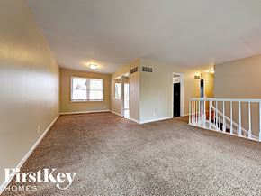 Aurora house for rent - an empty living room with carpeted floors and a staircase