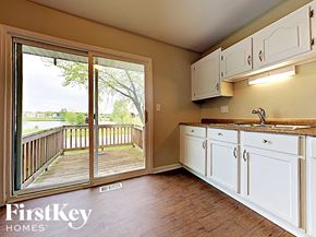 Aurora house for rent - a kitchen with white cabinets and a sliding glass door to a deck