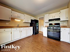 Aurora house for rent - a large kitchen with white cabinets and black appliances